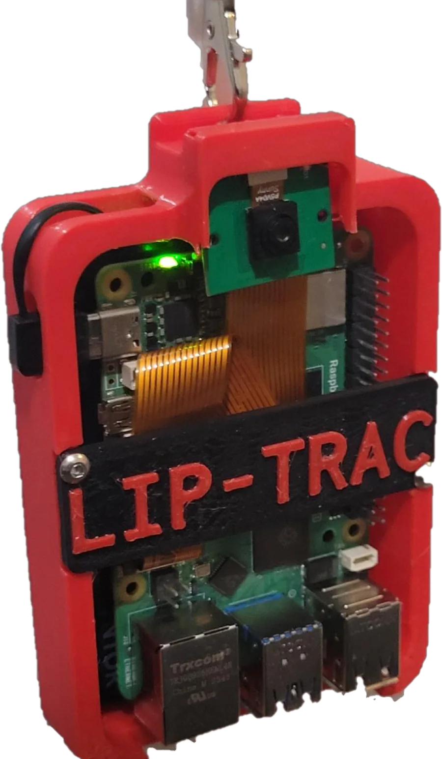 The assembled LIP-TRAC prototype hanging from a clip: a red 3D-printed case around a Raspberry Pi 5 with its status LED lit, a camera module at the top, and a black LIP-TRAC nameplate.